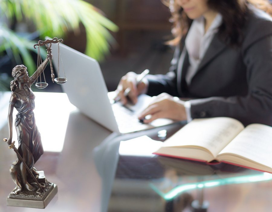 Lawyer office. Statue of Justice with scales and lawyer working on a laptop. Legal law, advice and justice concept Verpflichtende Nutzerkonten im E-Commerce: DSGVO auf dem Prüfstand