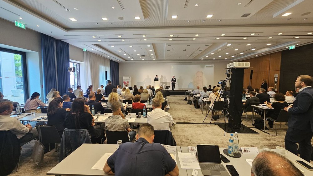 Der vollbesetzte Konferenzraum der Berliner Geldwäsche-Tagung zeigt zahlreiche Teilnehmende an den Tischen und eine professionelle Kameraausstattung für die Übertragung.